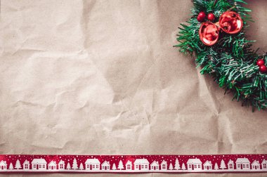Kırmızı Noel kurdelesi ve şenlikli çelenkli buruşuk kraft kağıdı..
