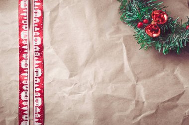 Kırmızı Noel kurdelesi ve şenlikli çelenkli buruşuk kraft kağıdı..