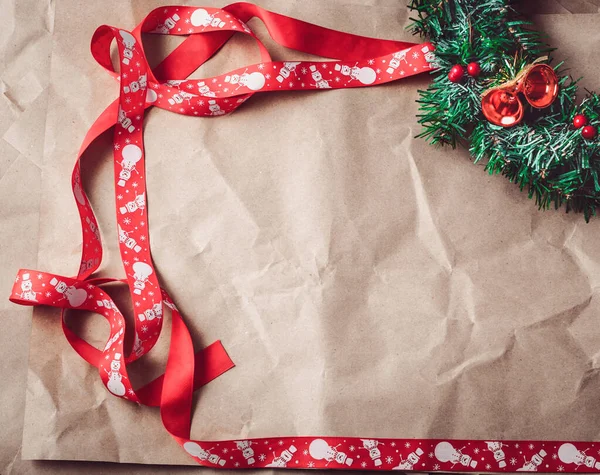 Смятая крафтовая бумага с красной рождественской лентой и праздничным венком . — стоковое фото
