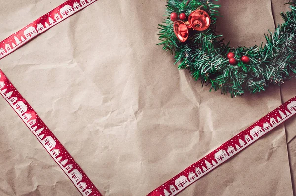 Carta kraft arruffata con nastro rosso di Natale e ghirlanda festiva . — Foto Stock