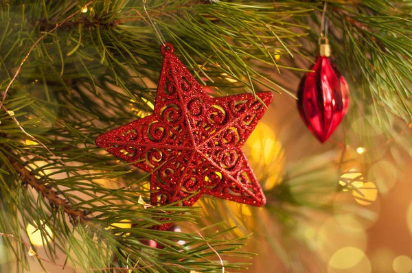 Christmas shiny red star toy on a christmas tree branch with holiday lights Royalty Free Stock Images
