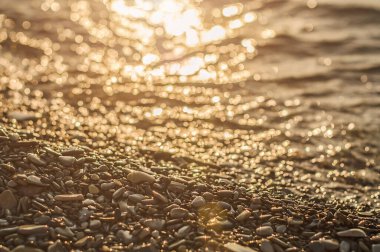 Gün batımında deniz sörfü. Karadeniz kıyısı. Deniz dalgalarıyla yıkanmış çakıl taşı. Seçici odak.