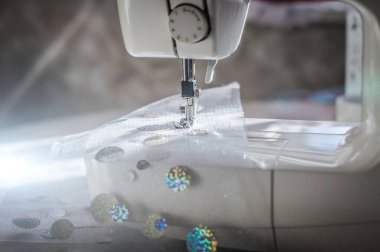 Dikiş makinesinde ışıldayan şenlikli kumaş. Noel tatili için kostüm üretimi.