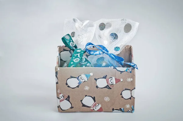Caja con regalos de Navidad empaquetados en bolsas brillantes y vendados con cintas azules y verdes sobre fondo blanco — Foto de Stock