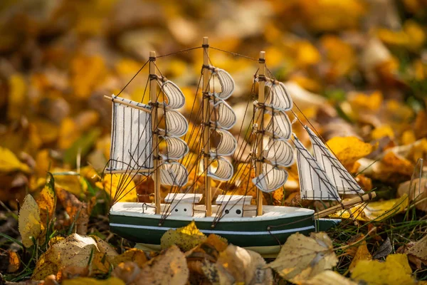 Model of a sailboat on autumn leaves. Photo of the layout of a wooden sailboat. Antique wooden miniature toy-reproduction of a model of a naval sailing ship.