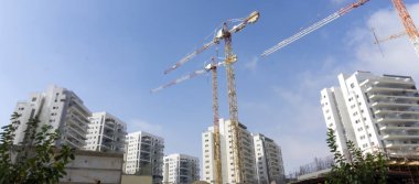 İsrail 'in Birüssebi kentsel manzarasında, sisli bir sabahta modern yerleşim binaları, yeşil bir şehir parkı, ağaçlar, su yansıması ve çağdaş mimari yer alıyor..