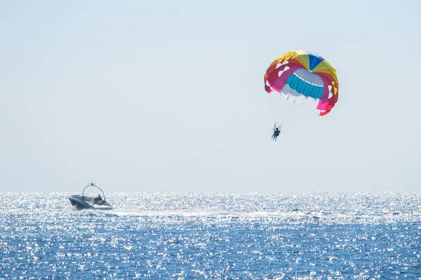 Parasailing denizde. Küçük bir motorlu tekne birkaç kişiyle renkli bir paraşüt kullanıyor. Seçici odaklanma. Yatay yönelim.