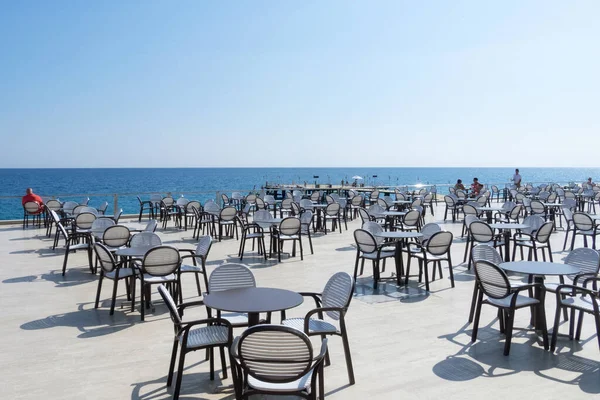 夏時間だ 海の見えるオープンエアのカフェ 海の近くに黒い縁の白いテーブルと椅子 水平方向 ストック写真