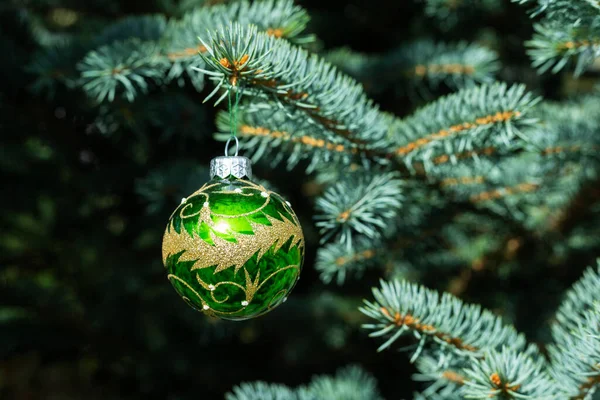 Mavi ladin üzerinde asılı yuvarlak yeşil Noel ağacı oyuncağı. Kapat..