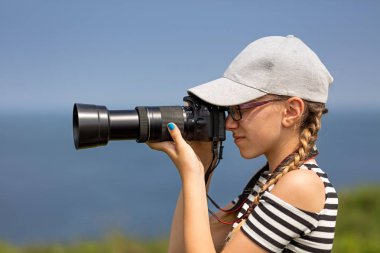 12 yaşındaki kız İrlandalı kayalıklarla güzel bir manzara içinde uzun bir lens ile fotoğraf çekmek