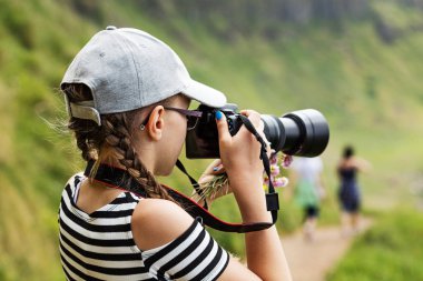 12 yaşındaki kız İrlandalı kayalıklarla güzel bir manzara içinde uzun bir lens ile fotoğraf çekmek