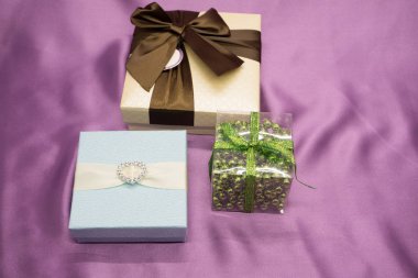 Üç beyaz hediye kutuları mor arka plan üzerinde kırmızı kurdele formla