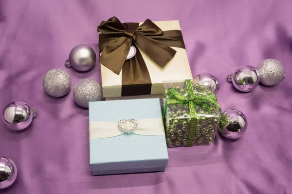 Üç beyaz hediye kutuları mor arka plan üzerinde kırmızı kurdele formla