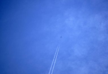 Beyaz yolcu uçağı yolcu ederken bu koyu mavi bulutlu gökyüzü beyaz contrails çekerek taşıma