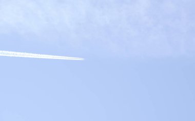 Beyaz çizgiler geride bırakarak mavi gökyüzü uçan uçak