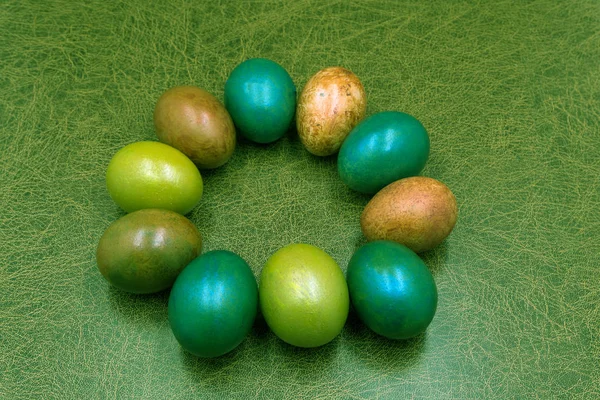 Renkli yumurta ve çiçek mavi zemin üzerine yapılmış yaratıcı Paskalya düzeni. Daire çelenk düz lay kavramı