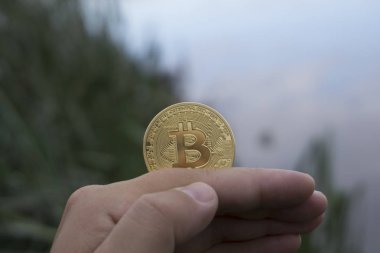 el bir altın tutan adam arka planda Bitcoin