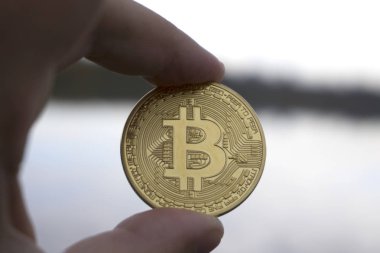 el bir altın tutan adam arka planda Bitcoin