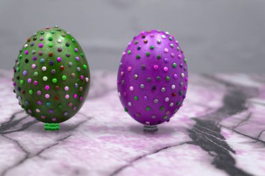 Bazı ev yapımı bir şekilde dekore edilmiş Paskalya yumurtaları, tek başıma, gri rustik ahşap bir masa üzerinde yapılan closeup farklı renkler tüyleriyle serpilir