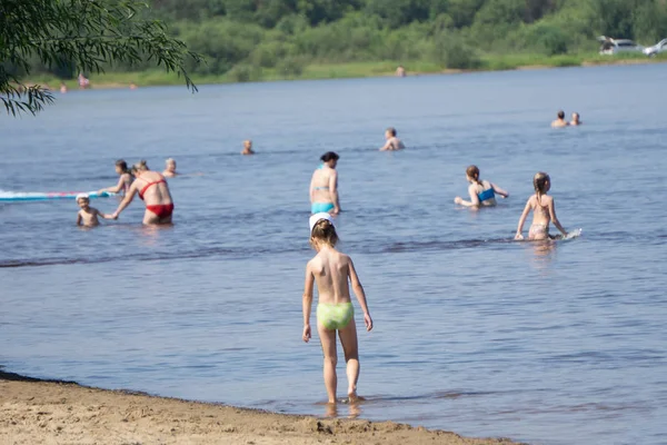 Het strand met kleurrijke paraplu's en mensen zwemmen in de Oceaan op een zomerdag. Het concept van tropische reizen en recreatie. — Stockfoto