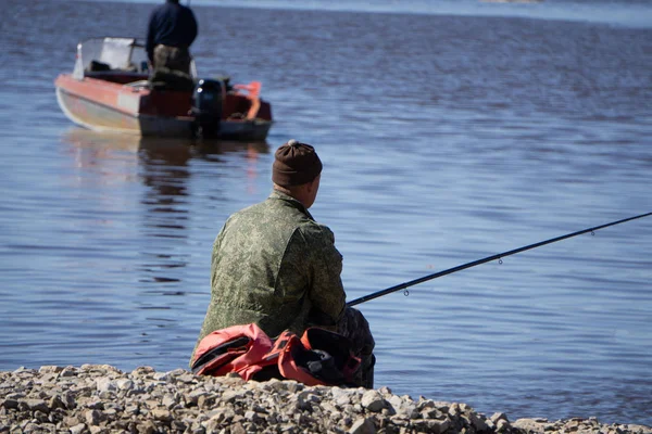 Coupé d'un homme attachant un appât à sa canne à pêche. Gros plan des mains d'une personne fixant un appât à une canne à pêche pour attraper du poisson . — Photo