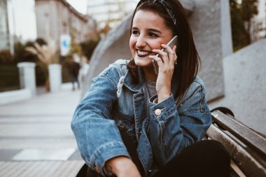 Serin ve güzel genç kadın şehirde telefonda konuşma. Kentsel tarzı