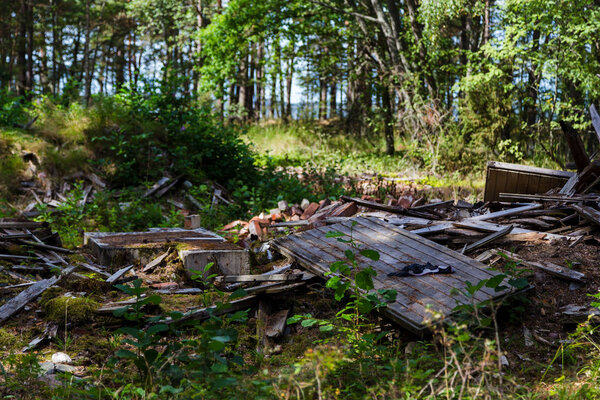 Remainings of a destroyed wooden building in the forest of Hanko Finland on a sunny day near the southernmost point of