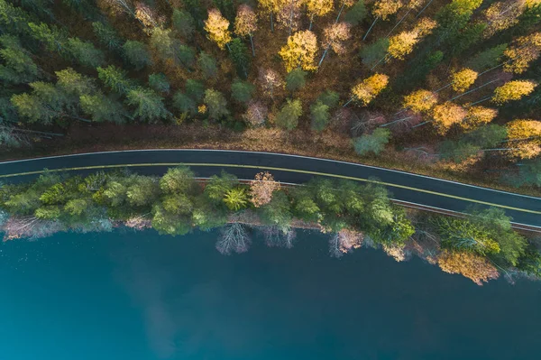 Above view from the air of a road by lake and autumn forest, Finland