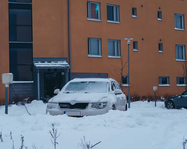 Автомобіль на стоянці будинку, вкритого м'яким шаром снігу — стокове фото
