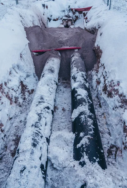 Two big pipes in the trench covered lightly with some snow on a winter day