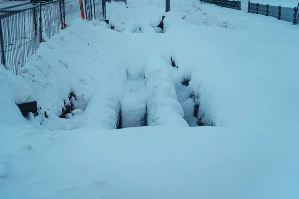 Due grandi tubature in trincea ricoperte di neve in una giornata invernale — Foto Stock