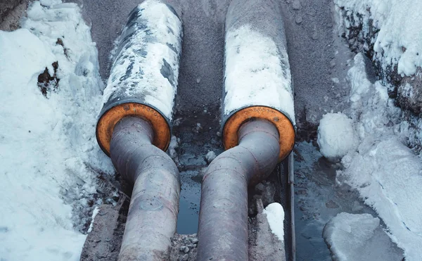 Två svetsade stålrör med isolering i en snöig dike — Stockfoto