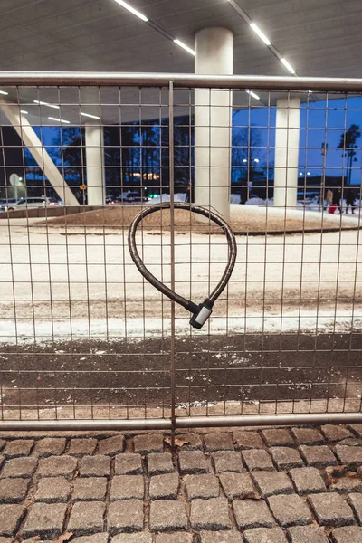 Bike lock locked at a steel fence on a winter day with snow