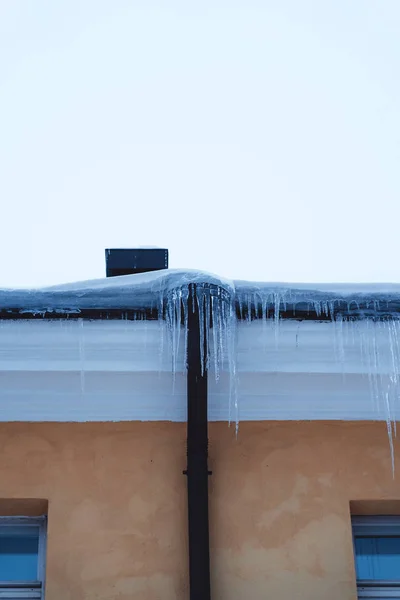 Snön börjar smälta på taket till en byggnad och hänger över taklinjen — Stockfoto