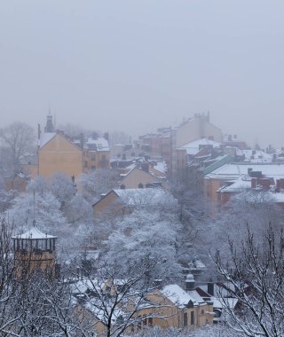 Sisli kış günü Stockholm'de bir tepede eski evleri ile kar üzerinde İsveç