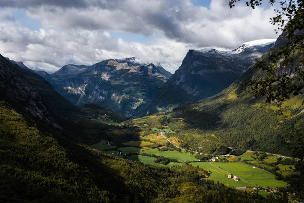 夏天的一天 挪威的山谷被群山环抱着 周围有一些小房子和一条路 — 图库照片