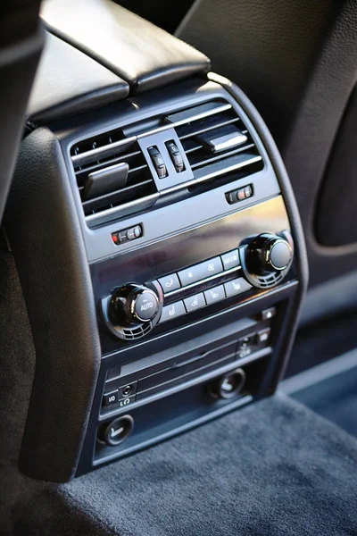 Modern luxury car climate control panel for passengers in the rear row with shallow depth of field. Four zone climate control. Car interior detail. Back passenger air vents and audio sistem headphone jacks.