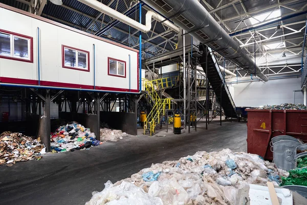 Department of manual waste sorting at modern waste plant with conveyor transports garbage inside drum filter or rotating cylindrical sieve with trommel for sorting pieces of garbage into fractions.