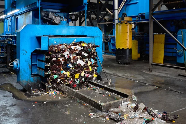 Modern waste sorting and recycling plant, hydraulic press makes wired bale from pressed PET bottles for processing and reuse of plastic. Concept of defence of environment by materials recycle.