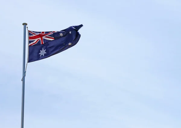 Australian flag flying in blue cloudy sky