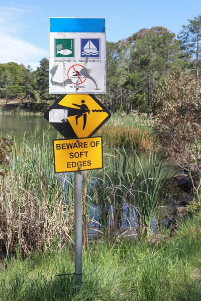 湖で黒と黄色のぼかしの注意の警告サイン — ストック写真