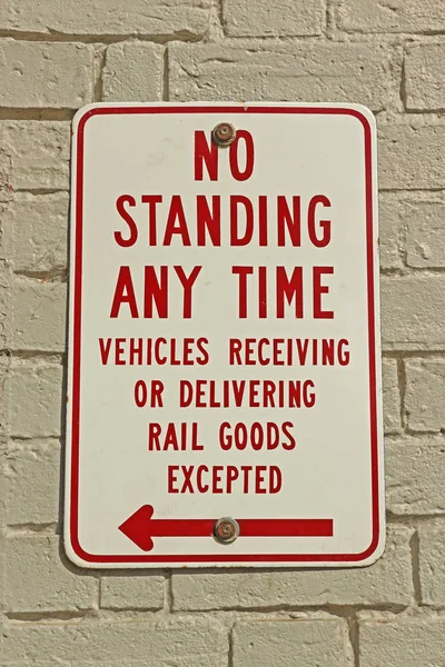 Red and white No Standing Any Time sign on a painted white brick wall — Stock Photo, Image
