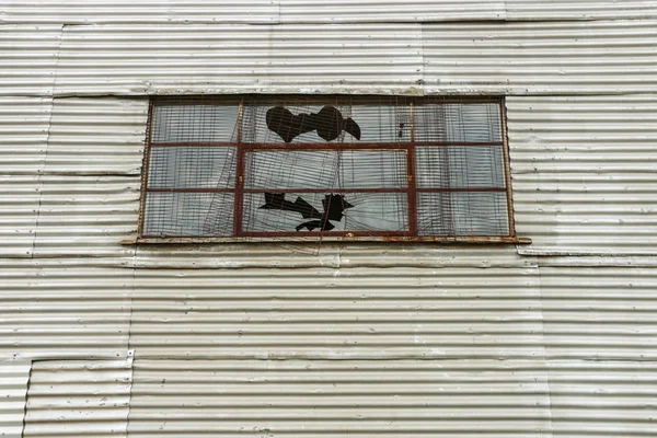 Ventana rota en edificio de hierro corrugado abandonado — Foto de Stock