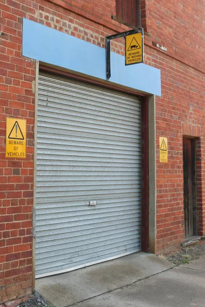 Negro y amarillo Cuidado con los carteles de vehículos en una puerta de garaje — Foto de Stock