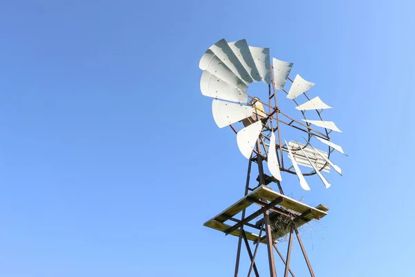 Um moinho de vento de aço em um céu azul na Austrália rural — Fotografia de Stock