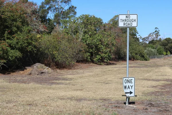 黒と白の通り道と金属製のポールに矢印の交通標識を持つ一方通行 — ストック写真