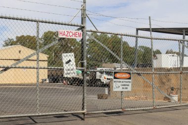 bir sanayi iş sitesinin dikenli tel çit üzerinde tehlikeli kimyasallar da dahil olmak üzere gözetim ve güvenlik uyarı işaretleri,