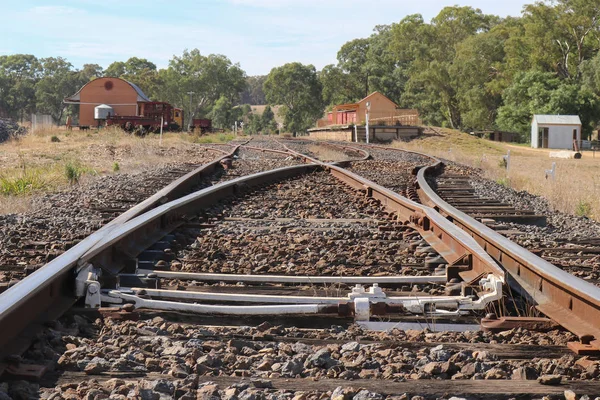Binari ferroviari incrociati in avvicinamento a una piattaforma della stazione ferroviaria — Foto Stock