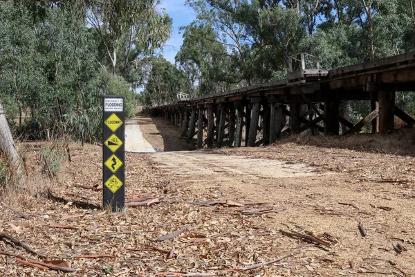 Zwart, wit en geel weg onderhevig aan overstromingen waarschuwing teken op een houten paal — Stockfoto