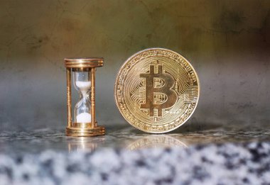 Fiziksel bitcoin ve kum saati zamanın geçtiğini gösteriyor.